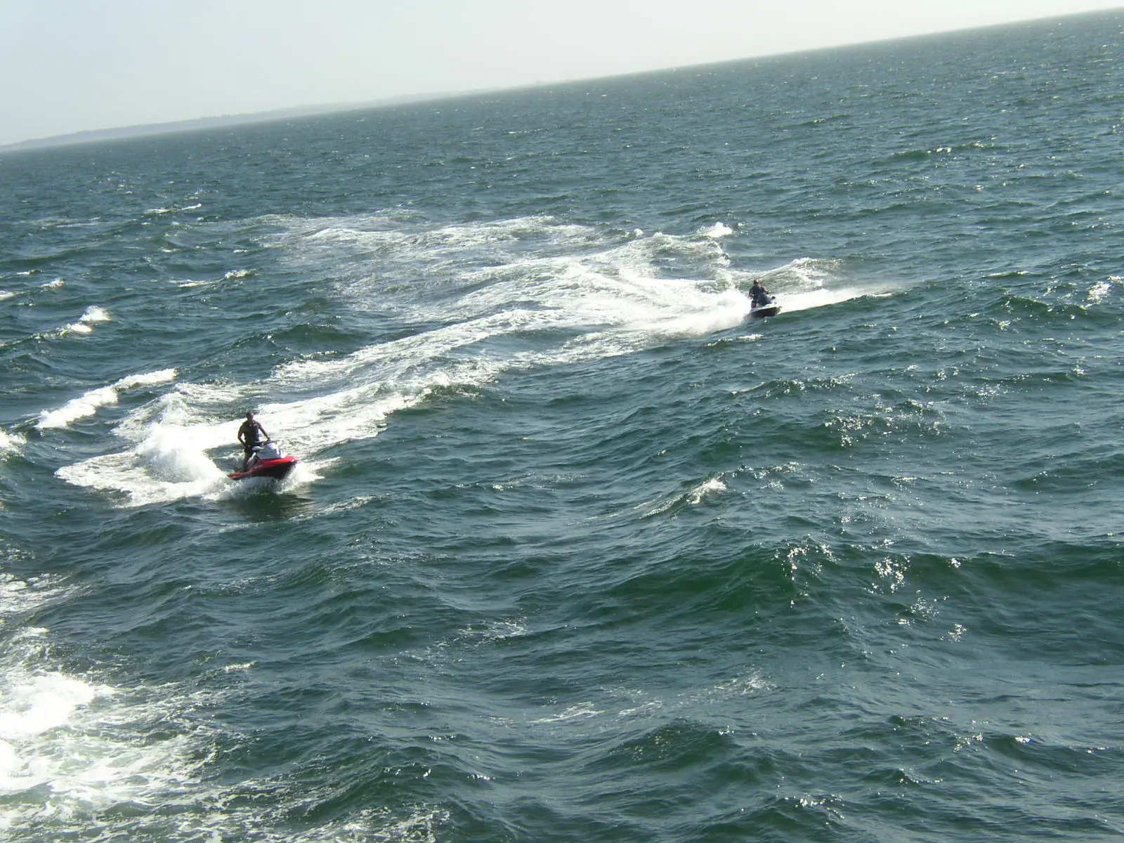 Two people are water skiing in the ocean.