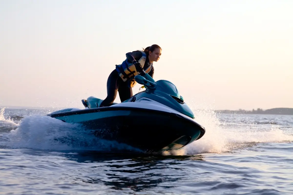 A woman is riding on the water with her jet ski.