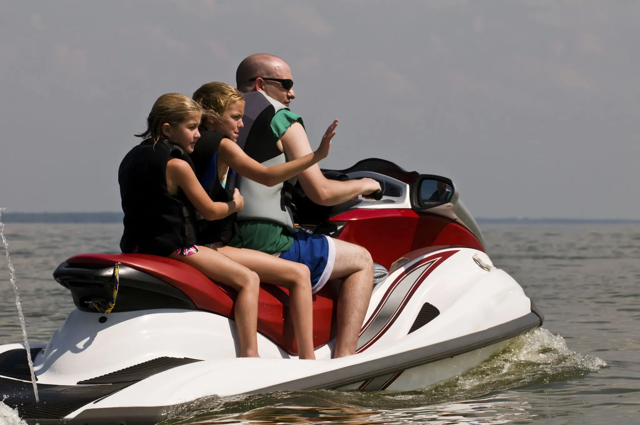 A man and two women on a jet ski.